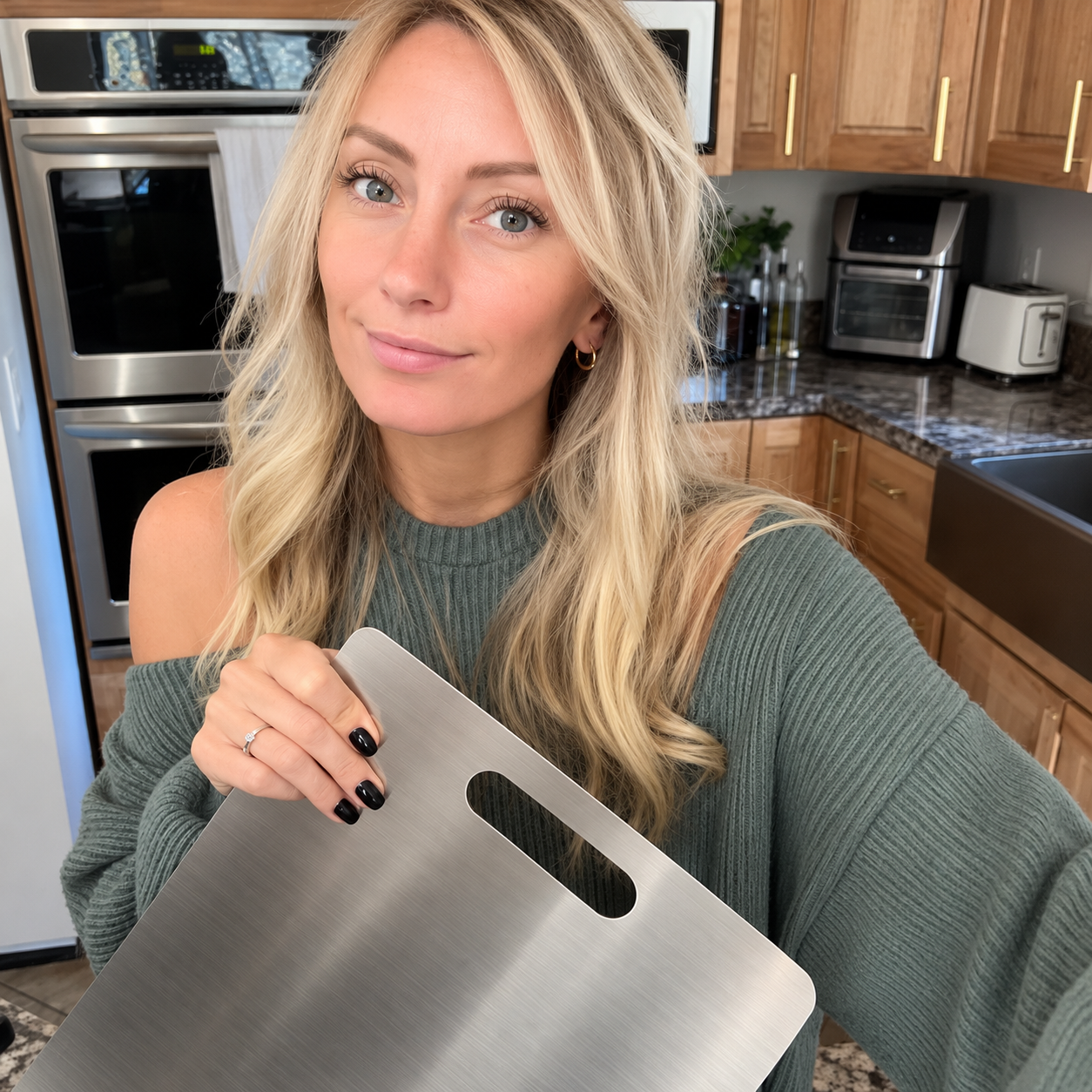 Linda holding a metallic cutting board in her kitchen